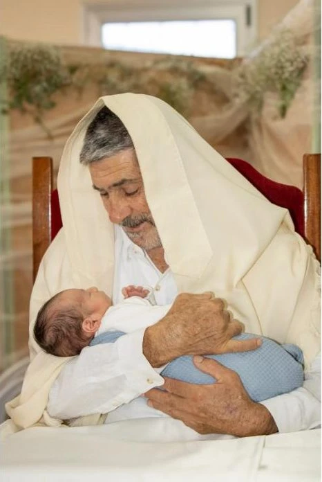 סבא מחזיק את התינוק בברית