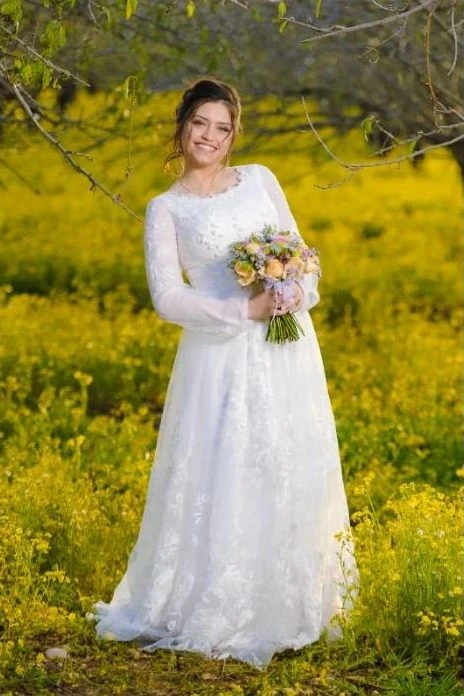 כלה בשמלה לבנה בשדה פרחים צהובים